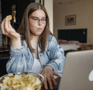 a woman eating chips while using a laptop