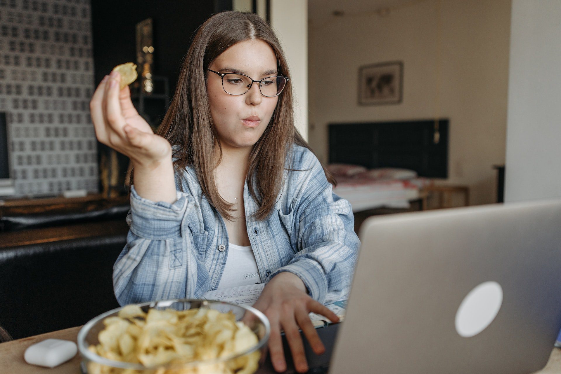 a woman eating chips while using a laptop